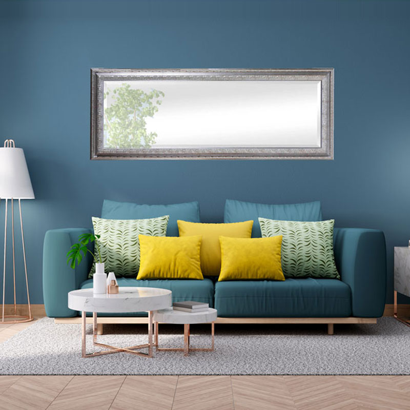 Silberner Wandspiegel eckig über Sofa in Wohnzimmer